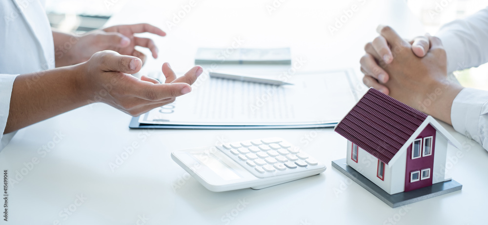 A real estate agent with a House model is talking to clients about buying home insurance. Home insurance concept A real estate agent with a House model is talking to clients about buying home insurance. Home insurance concept