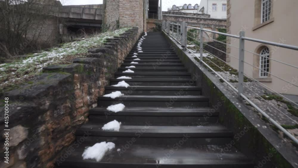 Slowly ascending an outdoors stone staircase, snow melting in the shadows Slowly ascending an outdoors stone staircase, snow melting in the shadows