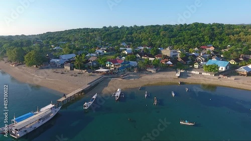 Traditional boats by pier in idyllic coastal village on Moyo Island, Indonesia photo