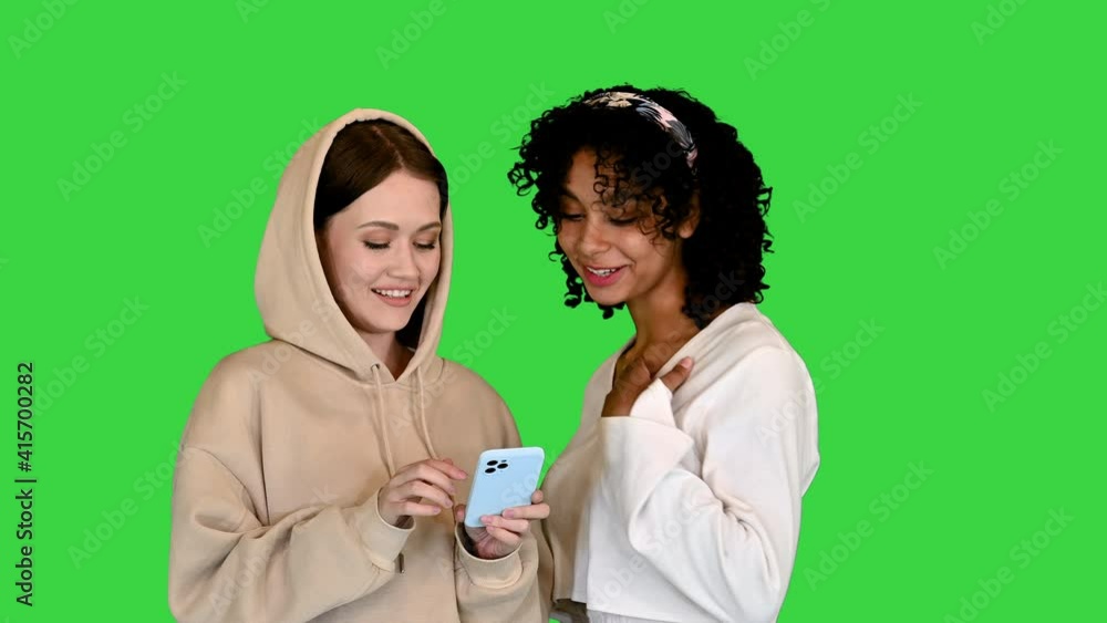 African American and a Caucasian girl surfing the mobile Internet on a Green Screen, Chroma Key. African American and a Caucasian girl surfing the mobile Internet on a Green Screen, Chroma Key.