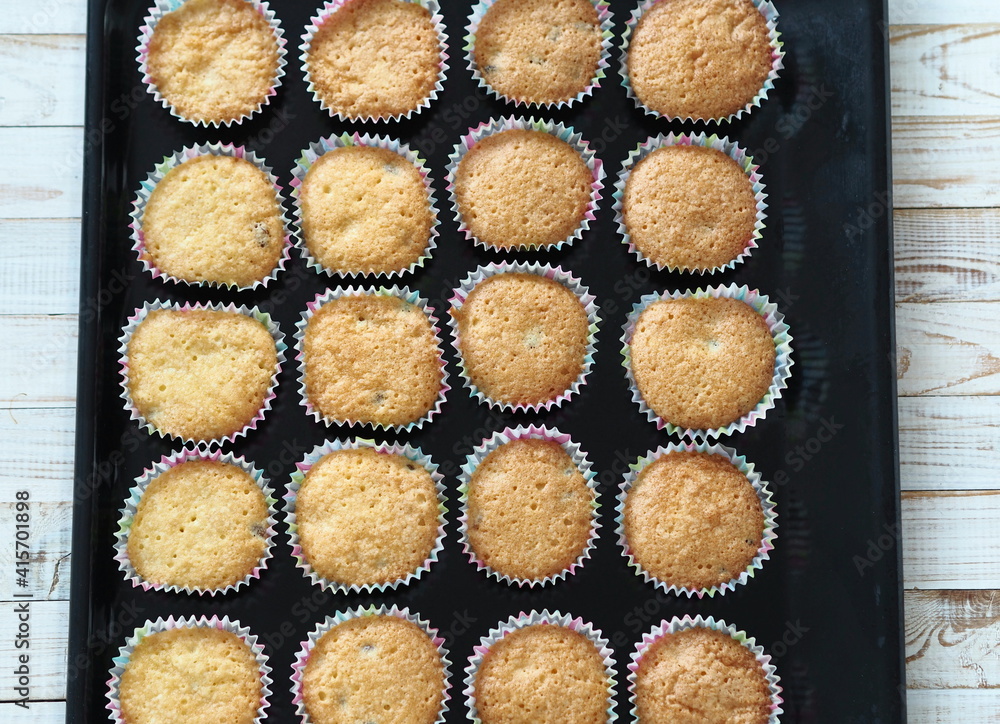 Freshly baked homemade raisin muffins in paper tins on a baking sheet from the kitchen oven.