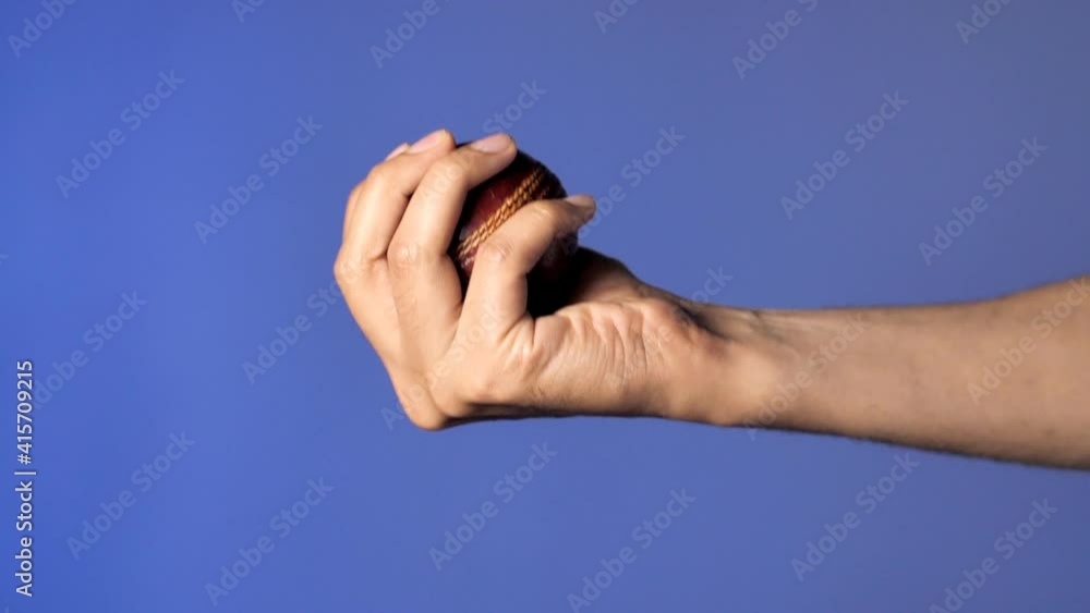 Indian bowler holding a red cricket duce ball dropping from the air ...