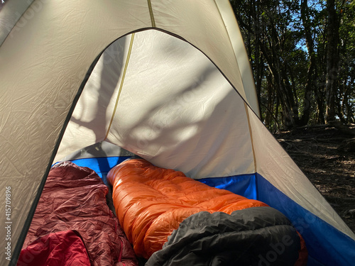 Look into a camping tent with colorful sleeping bags in mountain on sunny day, comfort is king when it comes to camping bags, and hikers top picks are a warm and cozy equipment for staying in mountain