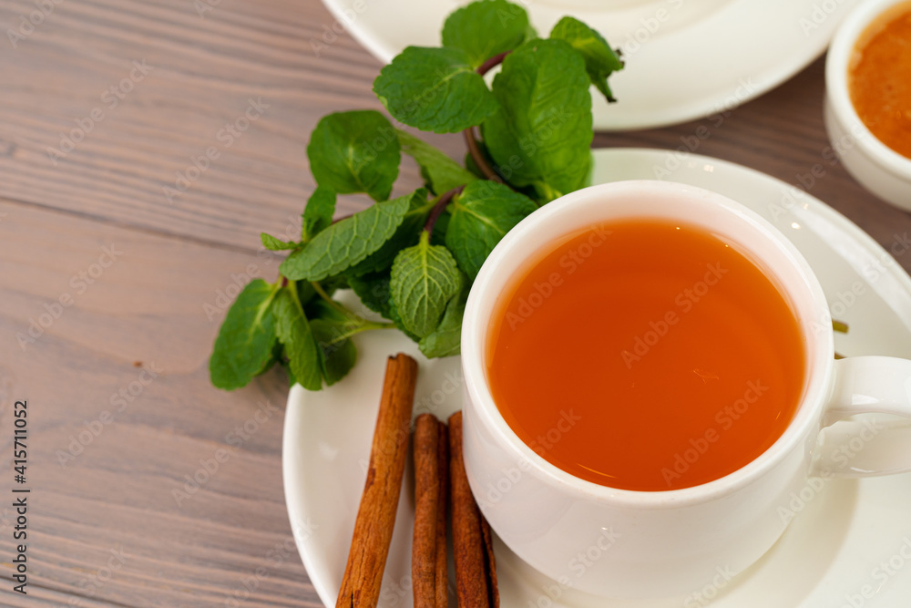 Black tea served with cinnamon sticks and mint on brown table