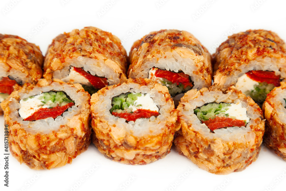 Sushi Roll with fried salmon in Teriyaki sauce on a white plate, ingredients Fried salmon, cream cheese, cucumber, baked pepper, flying fish roe, Spicy sauce, rice, nori. For the restaurant menu.
