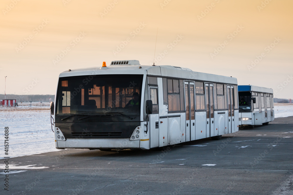 Two empty airport shuttle buses in a cold winter evening