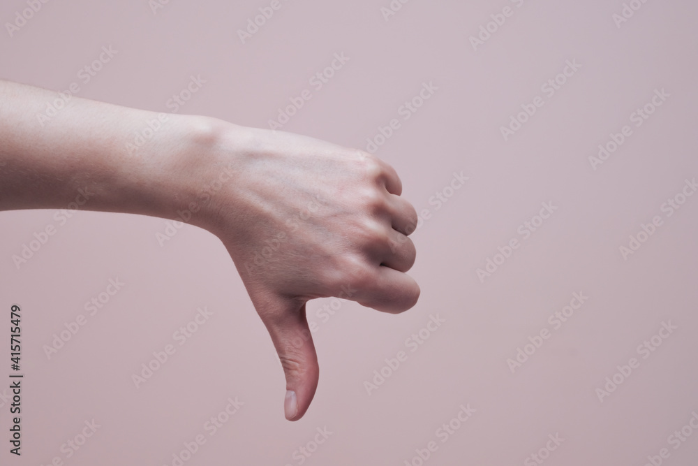 Female hand showing thumb down gesture. Hand signs communication concept. Closeup, copy space Female hand showing thumb down gesture. Hand signs communication concept. Closeup, copy space