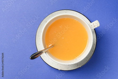 Cup of ginger citrus tea over blue background. Tea time concept.