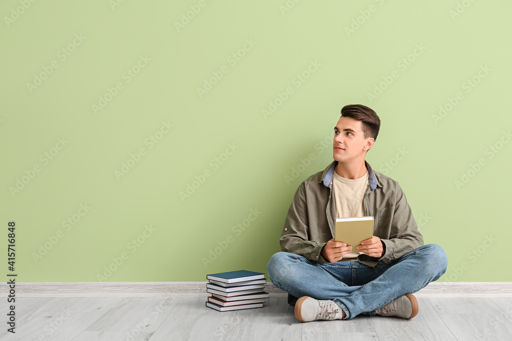 Young man with books near color wall Young man with books near color wall