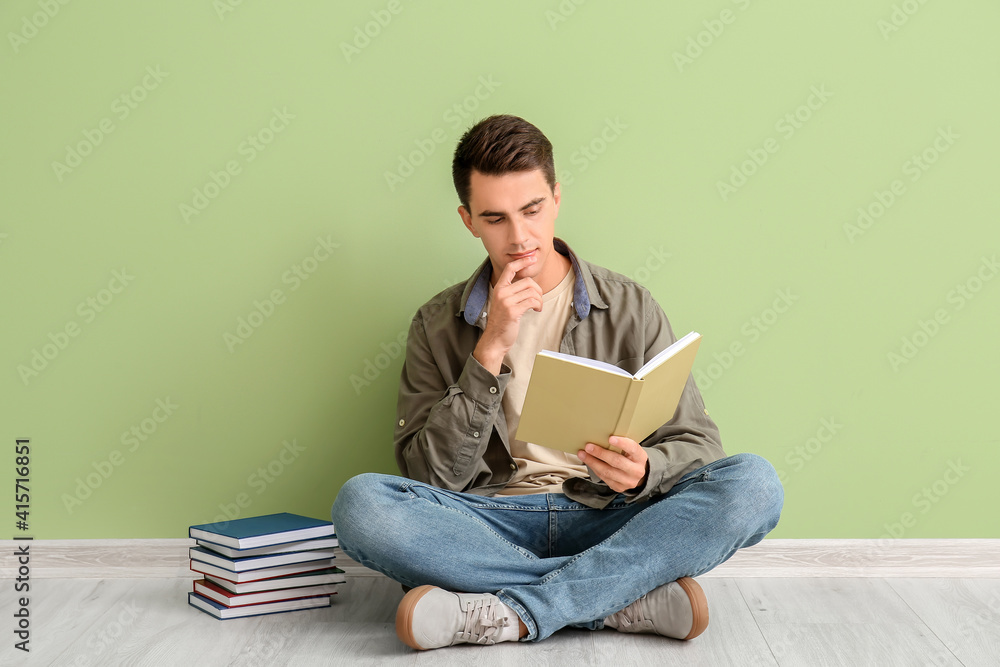 Young man reading books near color wall Young man reading books near color wall