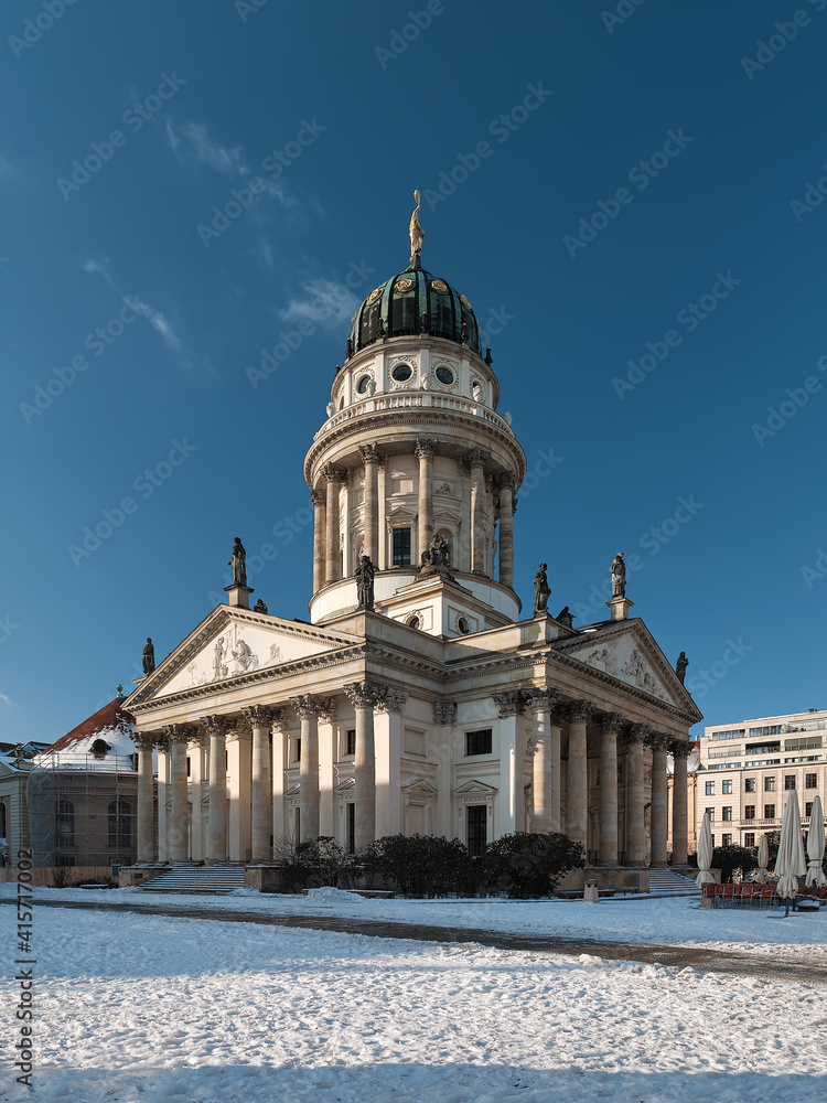 Gendarmenmarkt historic square in Berlin with French Cathedral. Picture taken n a bright Winter day with blue sky and snow.