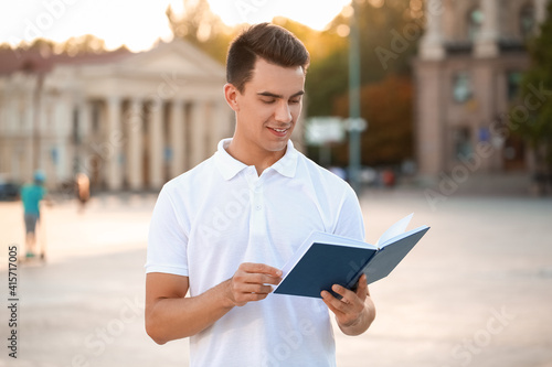 Young man reading book outd...