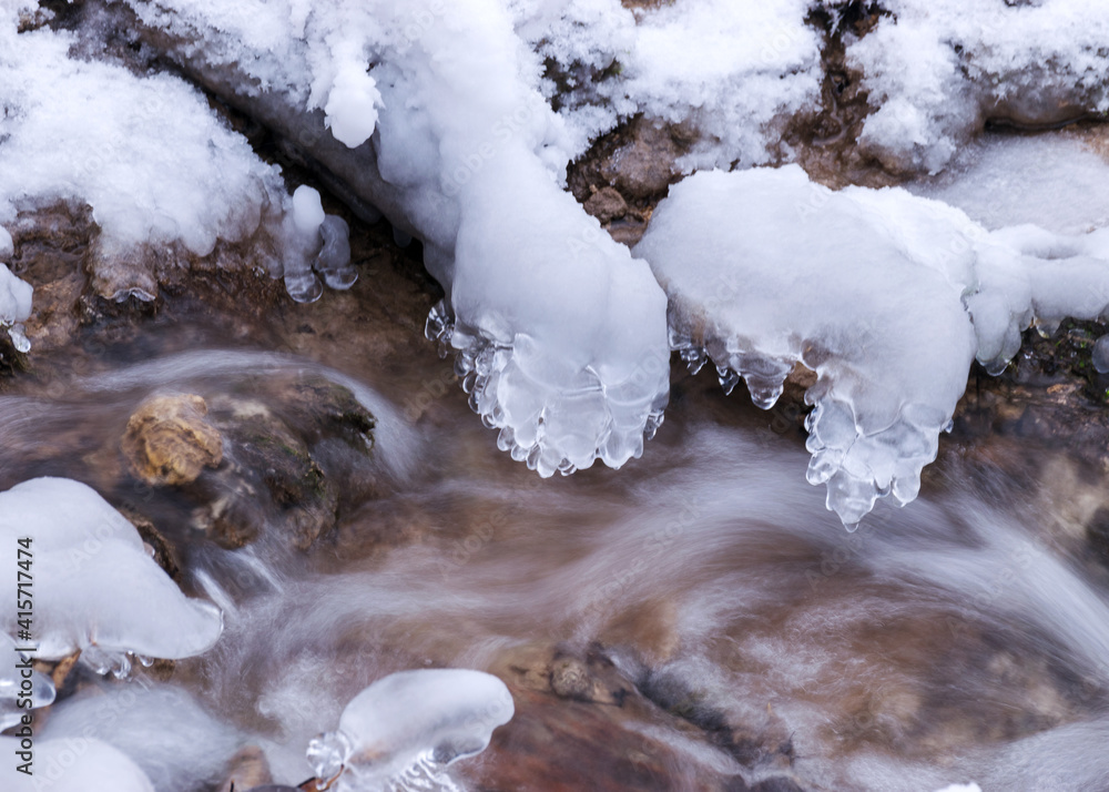 frozen fast flowing spring water, icy rocks and water stream, frosty tree roots, beautiful ice and water texture frozen fast flowing spring water, icy rocks and water stream, frosty tree roots, beautiful ice and water texture