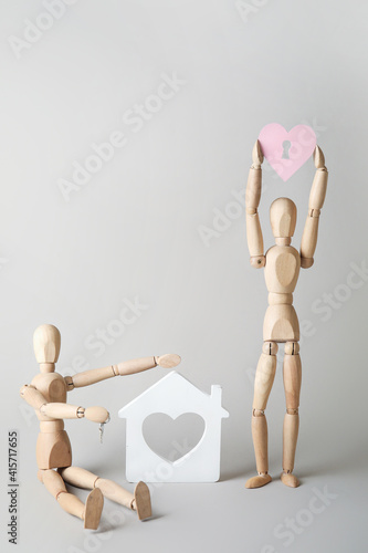 Wooden mannequins with pink heart and house model on light background