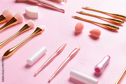 Set of makeup brushes, sponges and decorative cosmetics on color background