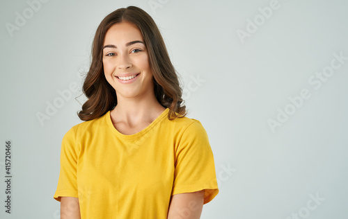 pretty brunette in a yellow t-shirt gray background smile emotions