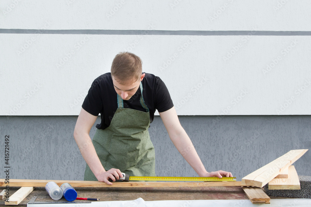 . A young male designer paints a wooden Board white with a brush. . A young male designer paints a wooden Board white with a brush.
