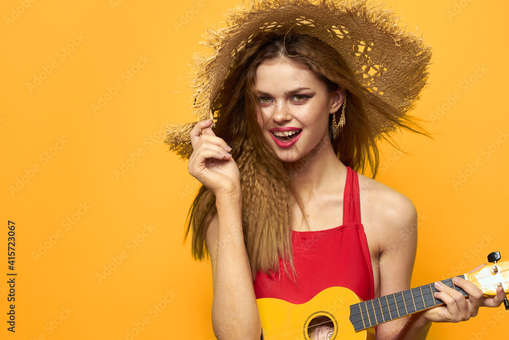 Cheerful woman in straw hat ukulele hands leisure lifestyle yellow background Cheerful woman in straw hat ukulele hands leisure lifestyle yellow background