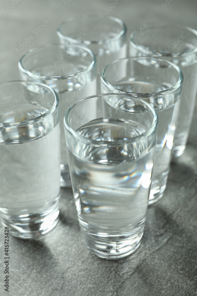 Shots with vodka on gray background, close up Shots with vodka on gray background, close up