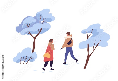 Happy people walking outdoor in winter among trees covered with snow. Man and...