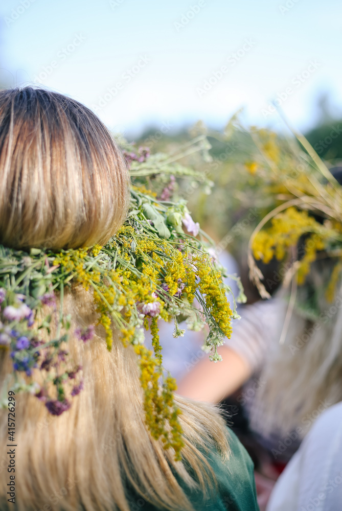 Naklejka premium Girl from the back in a wreath of flowers, wildflowers at the celebration of a traditional Slavic holiday Ivana Kupala