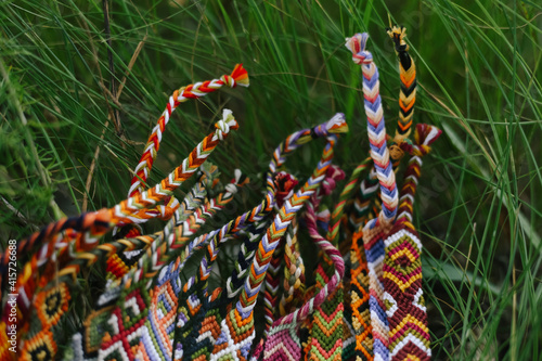 Wicker colored handmade bracelets from mouline thread lie in the grass up close. Background for needlework