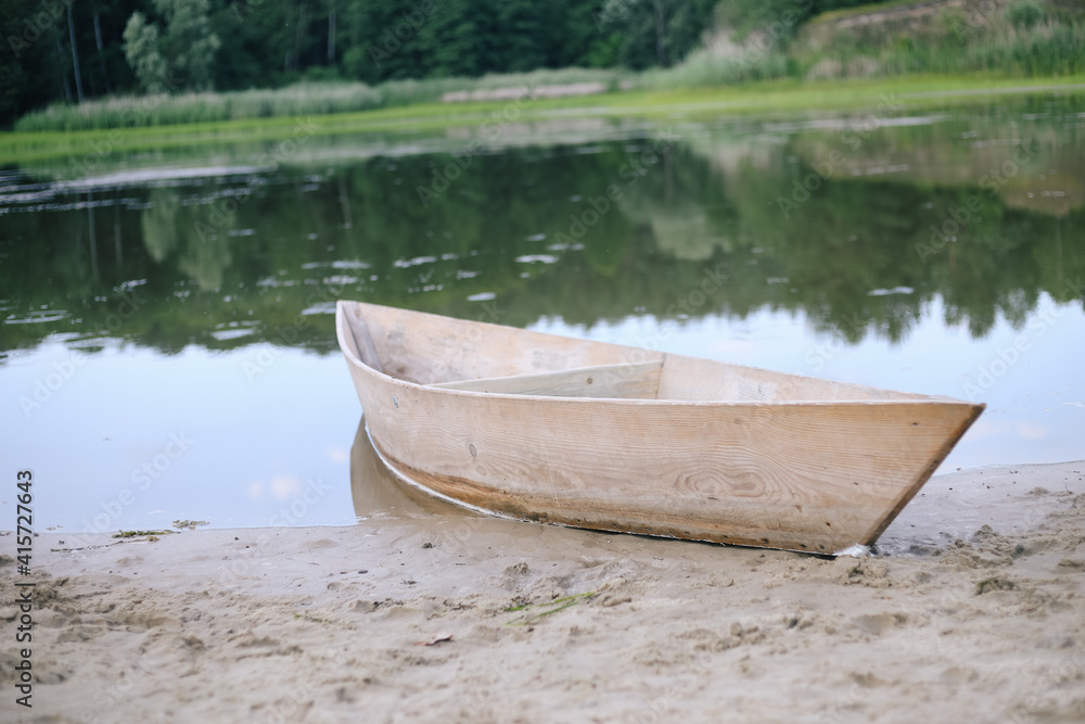 Old small wooden rowboat boat stands by the lake pond Old small wooden rowboat boat stands by the lake pond