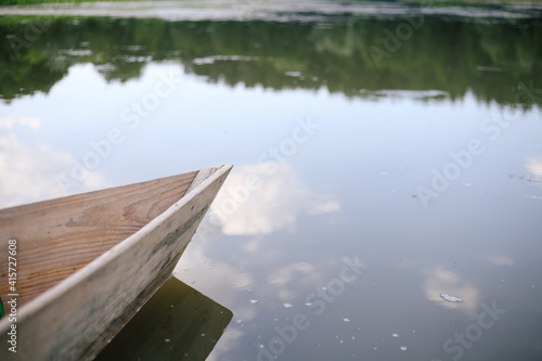 Old small wooden rowboat boat stands by the lake