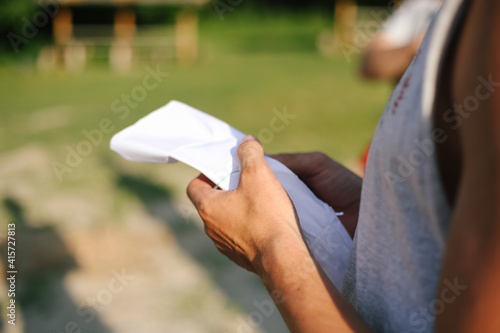 Close up of hand holding a sheet of white paper on a background of green grass in summer