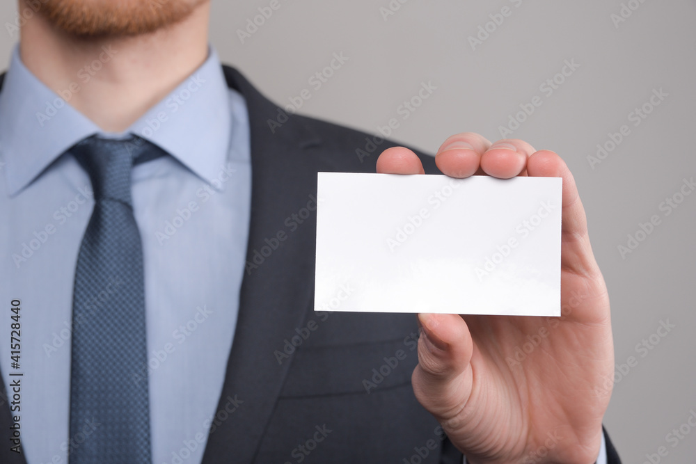 Businessman ,Business Man's hand hold showing business card - close up shot on grey background. Show a blank piece of paper. Paper visit card Businessman ,Business Man's hand hold showing business card - close up shot on grey background. Show a blank piece of paper. Paper visit card