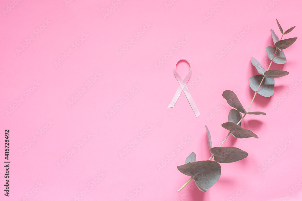 Pink ribbon describing the fight against breast cancer on a pink background with a branch of eucalyptus.