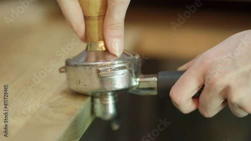 Preparing ground coffee with fresh coffee tamping. Close-up. Tamping freshly ground coffee into a horn, a holder of a coffee machine. photo