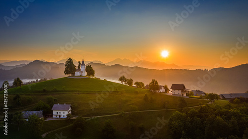 Wallpaper Mural Skofja Loka, Slovenia - Aerial panoramic view of amazing golden sunrise at the beautiful hilltop church of Sveti Tomaz (Saint Thomas) with and the Julian Alps at background at summer time Torontodigital.ca