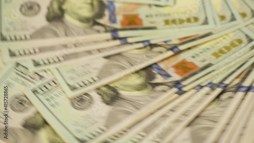 One hundred US dollar banknotes are circling.