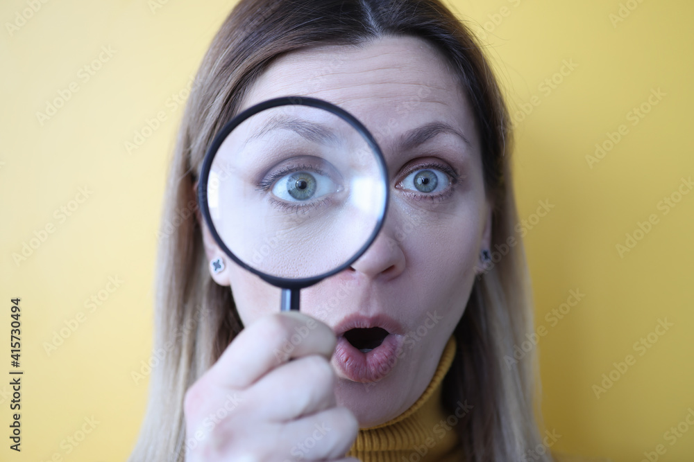 Woman with open mouth looking through magnifying glass Woman with open mouth looking through magnifying glass