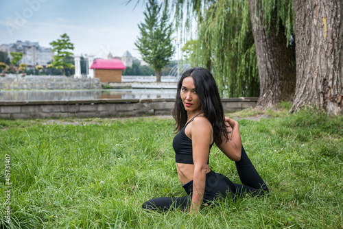  Beautiful fitness trainer doing yoga exercises on stretching and flexibility near lake