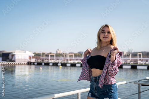 pretty young woman in casual wear standing in the city park near the pond summer day © RomanR