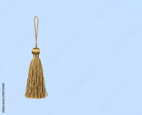 Golden silk tassel isolated on blue background for creating graphic concepts