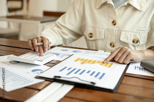 Businesswoman examining company finance documents in the office, corporate finance documents are displayed in a chart.