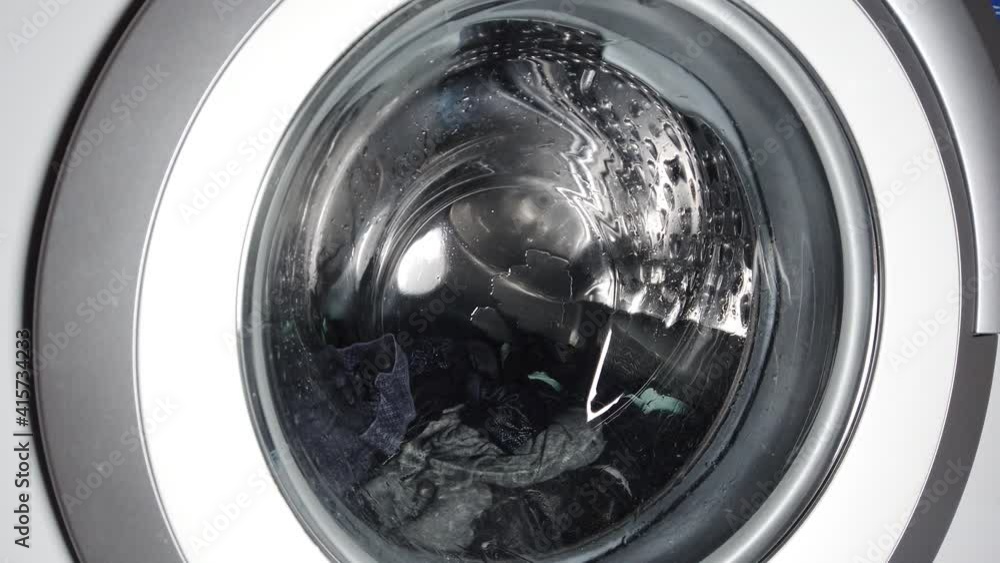 Washing clothing in generic domestic washing machine. Close up video of spinning washing machine drum. Washing clothing in generic domestic washing machine. Close up video of spinning washing machine drum.