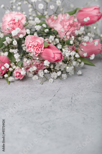 On a gray concrete background  pink tulips and carnations. Selective focus. 