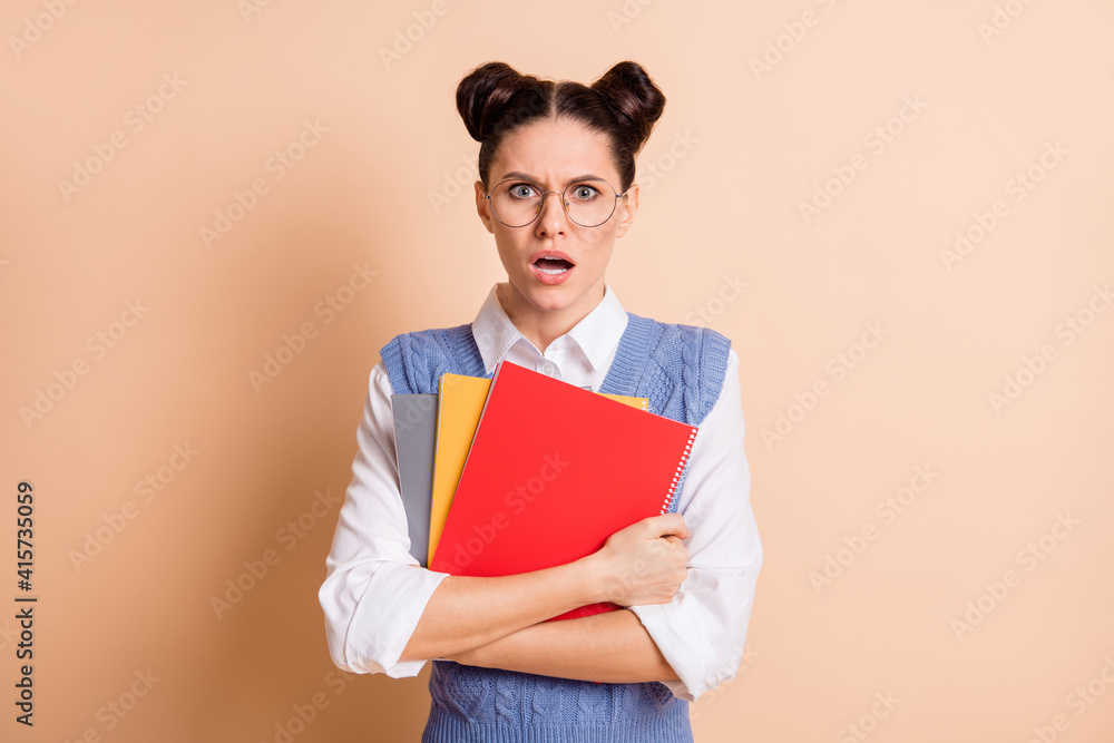 Photo of brunette impressed sad lady hold planners open mouth wear spectacles white shirt blue vest isolated on beige color background Photo of brunette impressed sad lady hold planners open mouth wear spectacles white shirt blue vest isolated on beige color background
