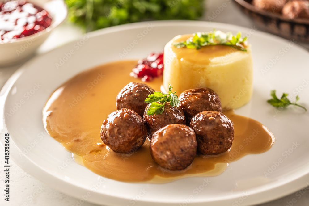 Plate serving Swedish meatballs kottbullar in sauce with mashed potatoes and cranberry sauce Plate serving Swedish meatballs kottbullar in sauce with mashed potatoes and cranberry sauce