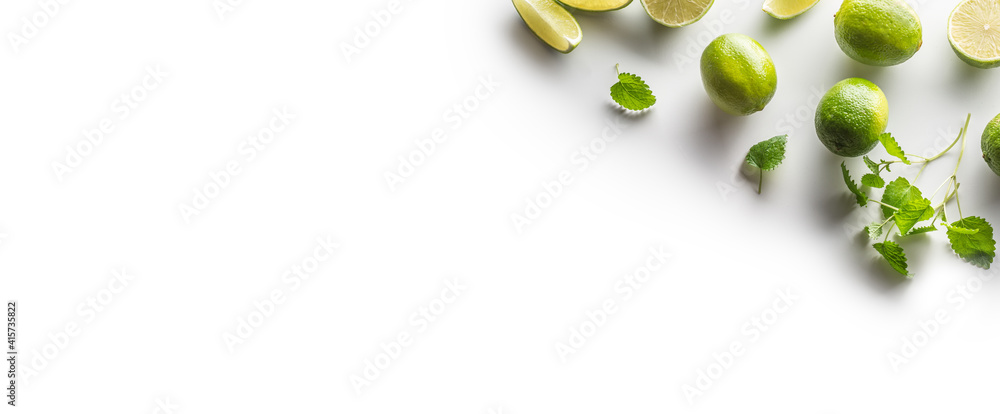 Sliced and whole limes with mint leaves on an isolated white banner background Sliced and whole limes with mint leaves on an isolated white banner background