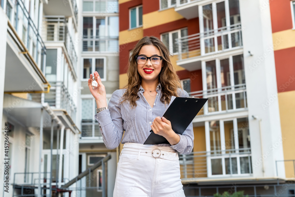 portrait of a realtor woman standing in front of a new house