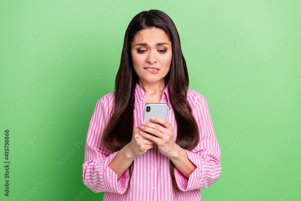 Portrait of attractive worried puzzled confused girl using device browsing bad news isolated over green pastel color background Portrait of attractive worried puzzled confused girl using device browsing bad news isolated over green pastel color background