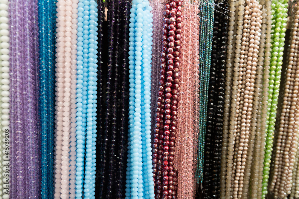 Strands of multicolored semiprecious stones offered for sale on display in bijouterie store
