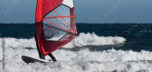 Windsurfer surfing the wind on waves in ocean sea 