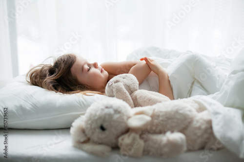 Beautiful little girl sleeping sweetly in a white bed