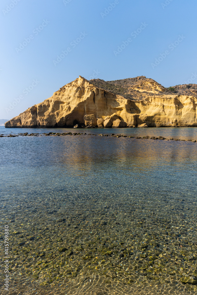 vertical view of calm idyllic ocean water in the Mediterranean with yellow sandstone cliffs behind